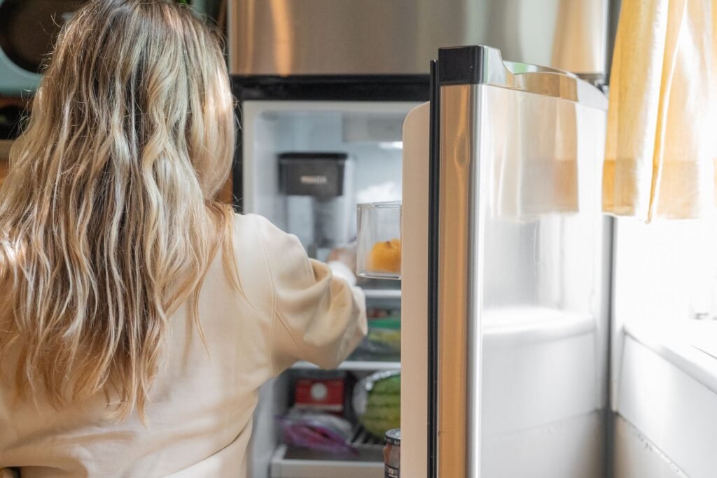 Réfrigérateur qui ne refroidit plus : cliente qui vérifie l’intérieur du frigo